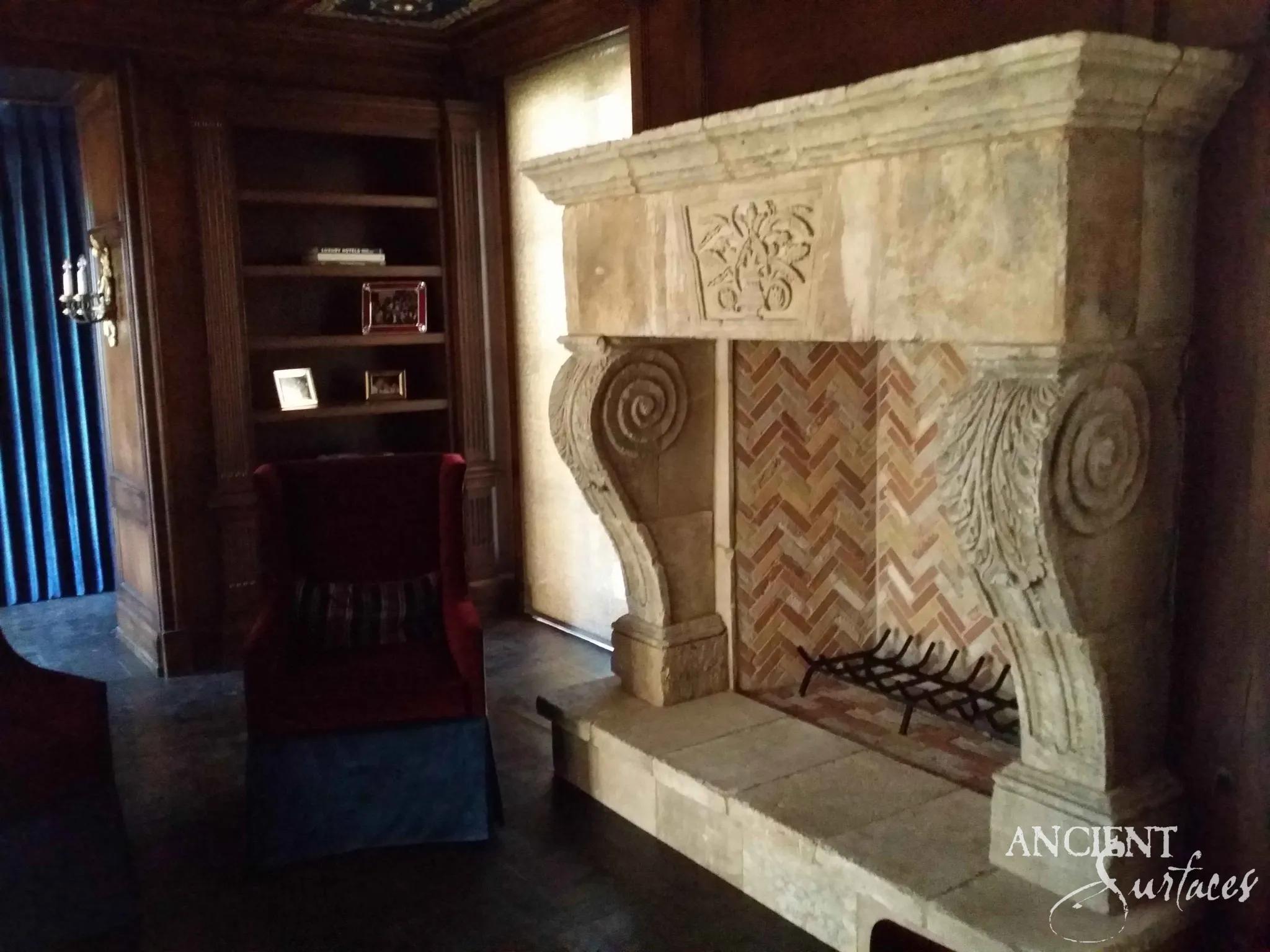 Monumental reclaimed limestone fireplace mantel with spiral-volute corbels in a panelled study