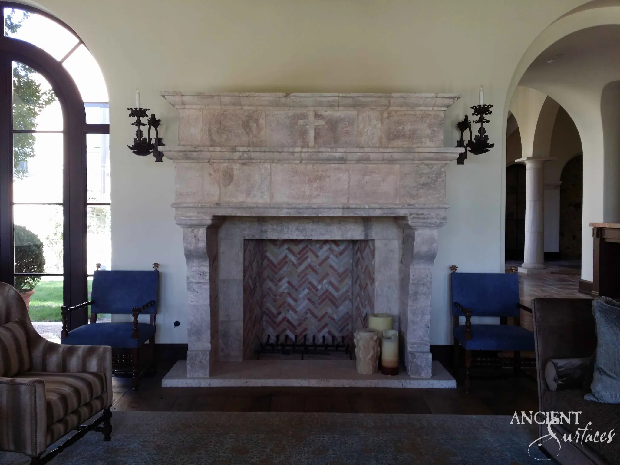 Monumental reclaimed limestone overmantel with a carved cross above a herringbone firebox