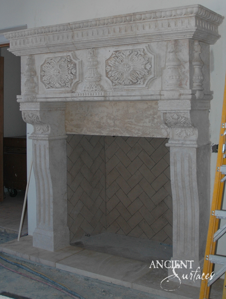 Carved reclaimed limestone fireplace mantel with acanthus-rosette panels and a fluted urn